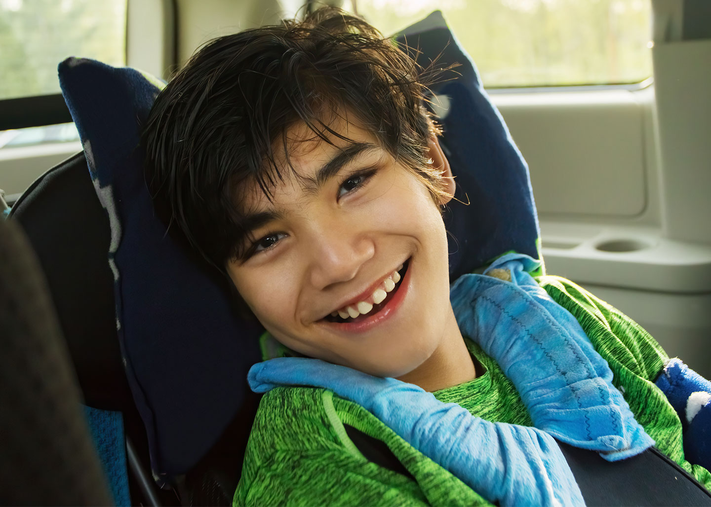 boy smiling at camera in the back of a car