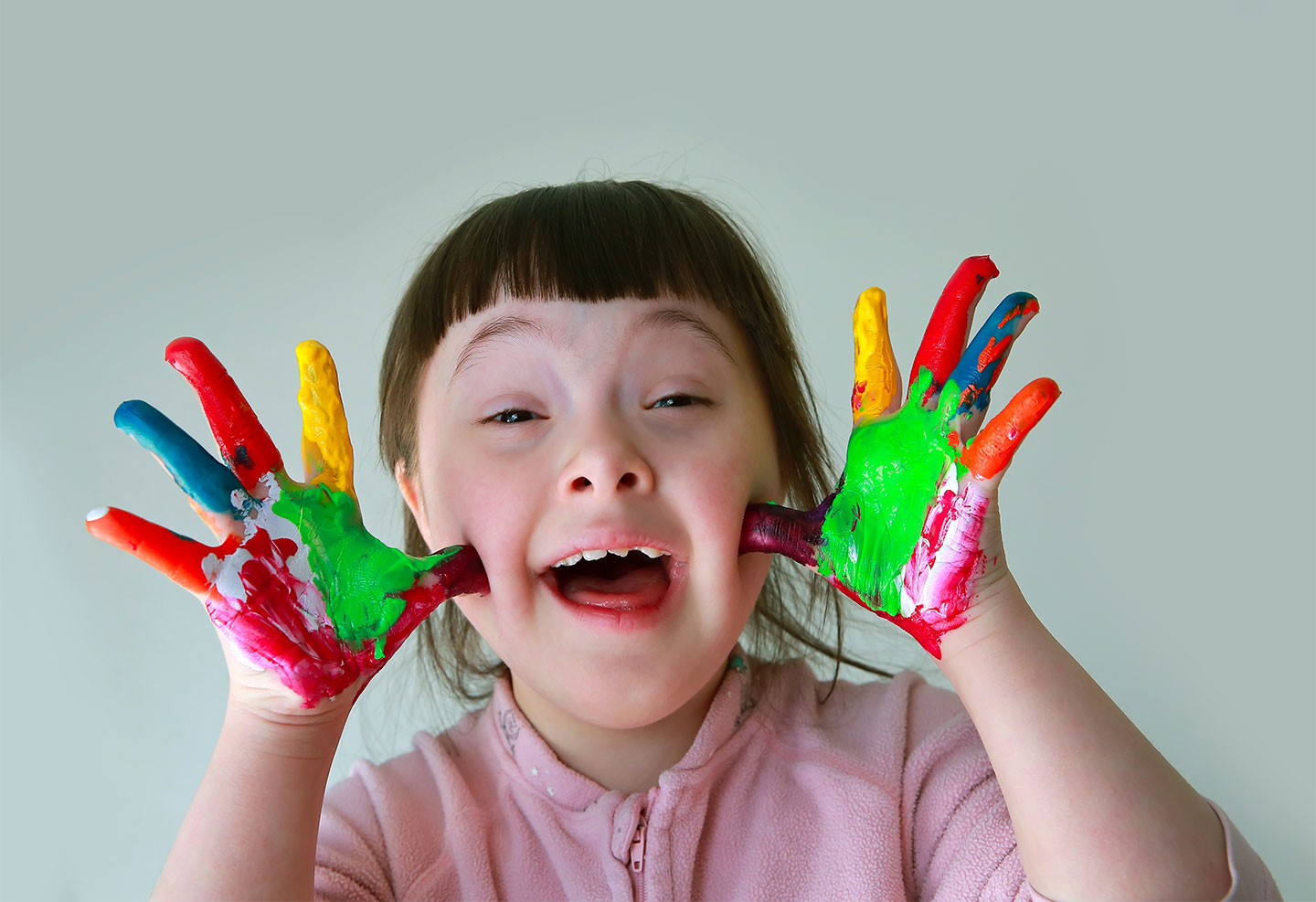 smiling downs syndrome girl with paint on hands